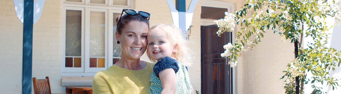 Mother and daughter standing in front of house