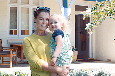 Mother and daughter standing in front of house