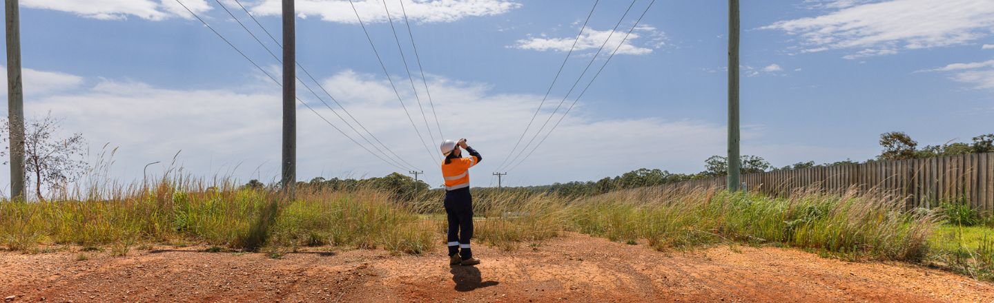 Worker looking up at power poles