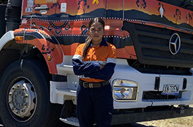Worker standing in front of a truck with their arms folded