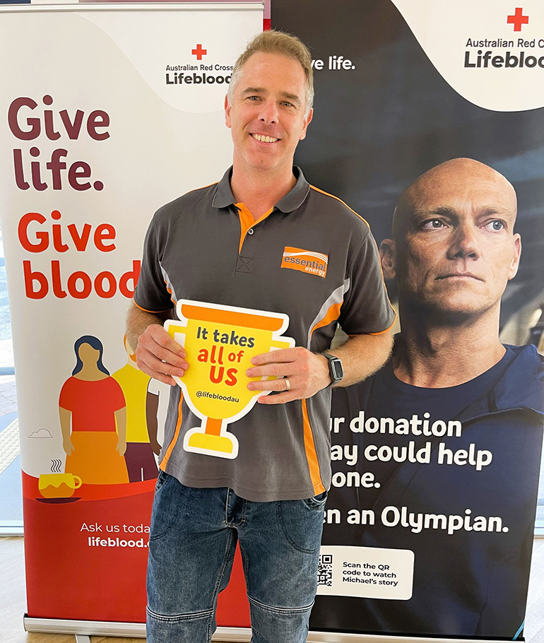 Aaron standing in front of a banner after giving blood