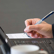 Writing on a notepad next to a laptop