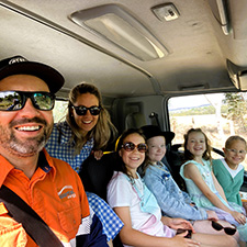 Two adults and four kids sitting in a truck smiling