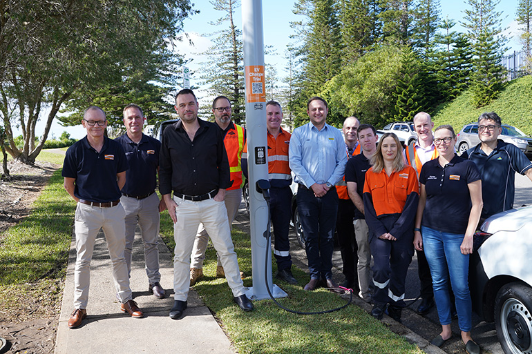 People standing near a streetlight with an EV charger