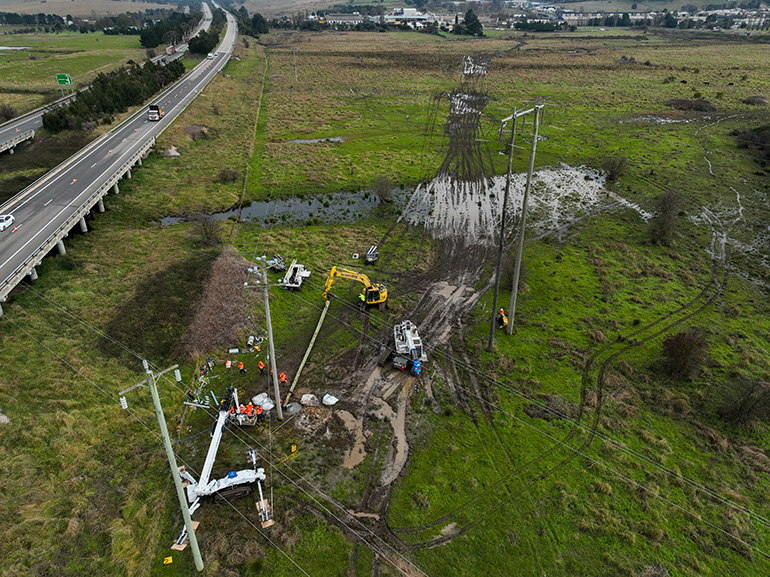 Workers changing a pole near a highway