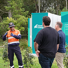 Three people standing near a community battery