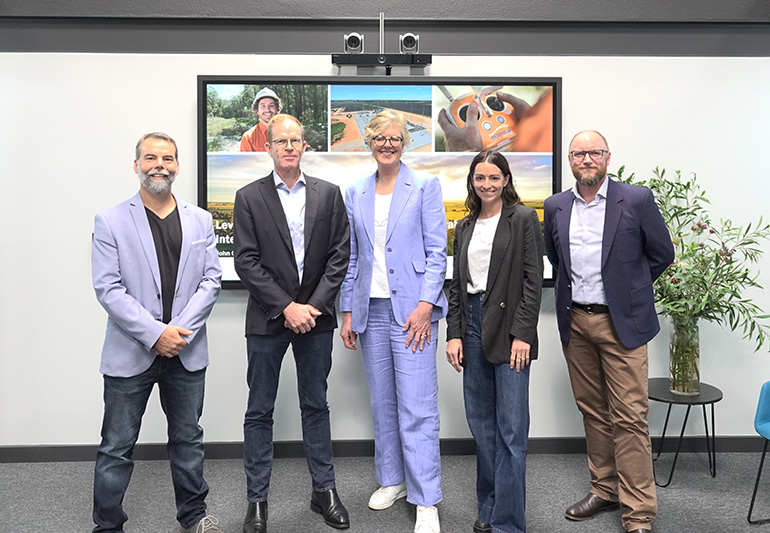 Five people standing in front of a presentation screen