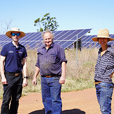 Three people standing in front of solar panels