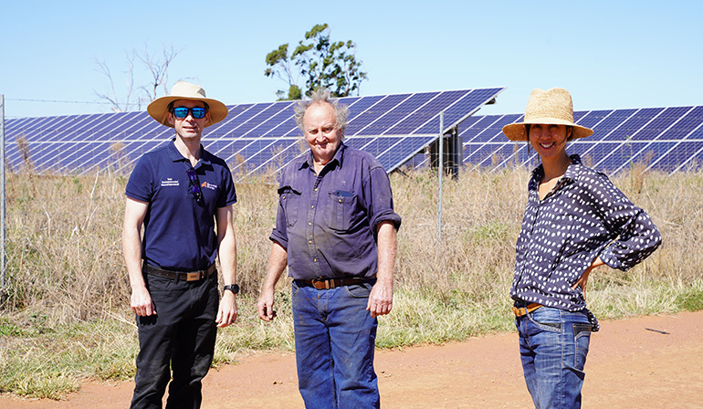 Three people standing in front of solar panels