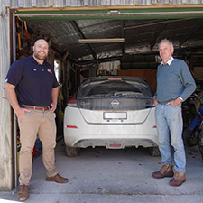 Two people standing near an electric car