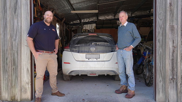 Two people standing near an electric car