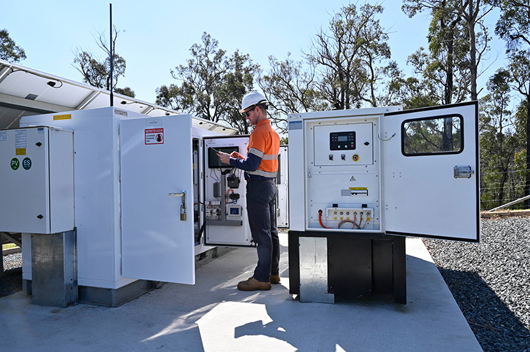 Worker standing among battery cabinets