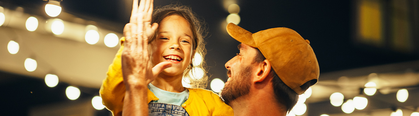 A father and daughter with lights in the background