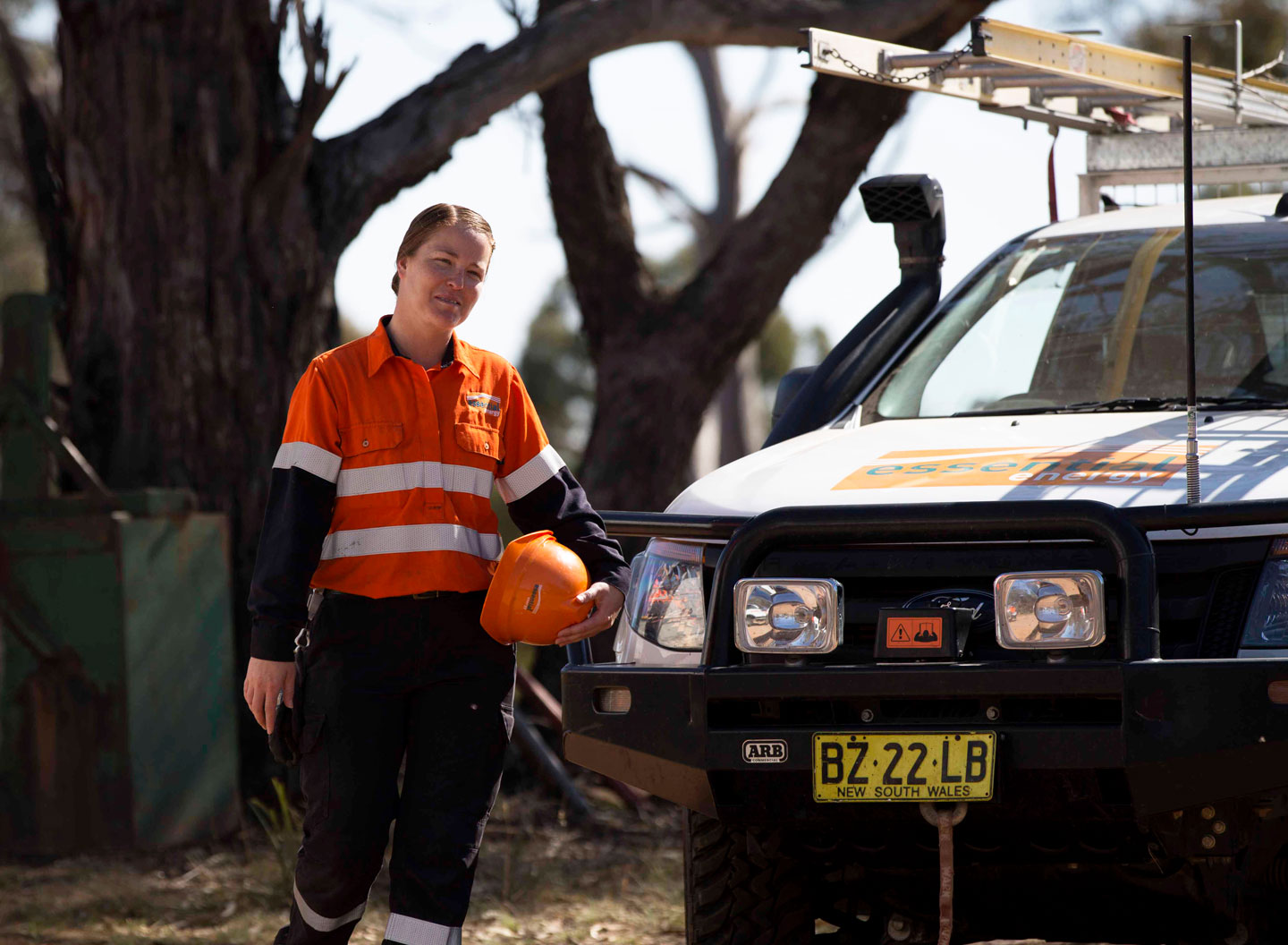 Female employee standing next to ute wearing personal protection equipment